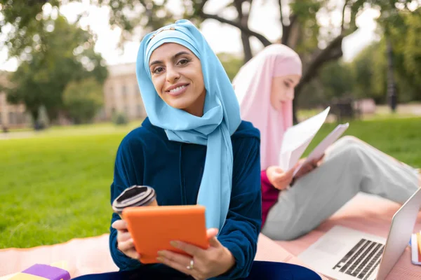 Mahasiswa muslim mengenakan hijab biru memegang tablet dan kopi — Stok Foto