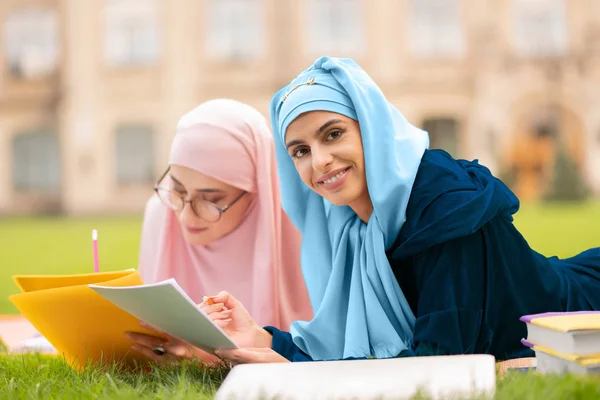 Close up of student wearing hijab holding test sheet and pencil