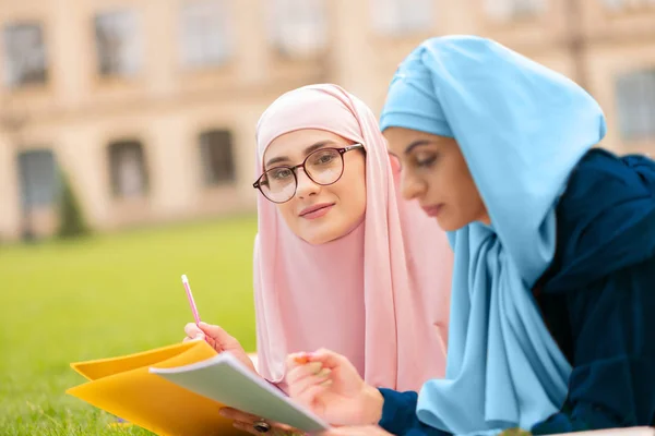 友人と勉強しながら微笑む青いヒジャーブの女性 — ストック写真