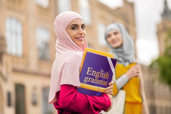 英語の文法書を持つ暗い目のイスラム教徒の学生 — ストック写真