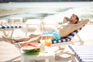 Güneşlenirken güneşli havanın tadını çıkaran yakışıklı adam