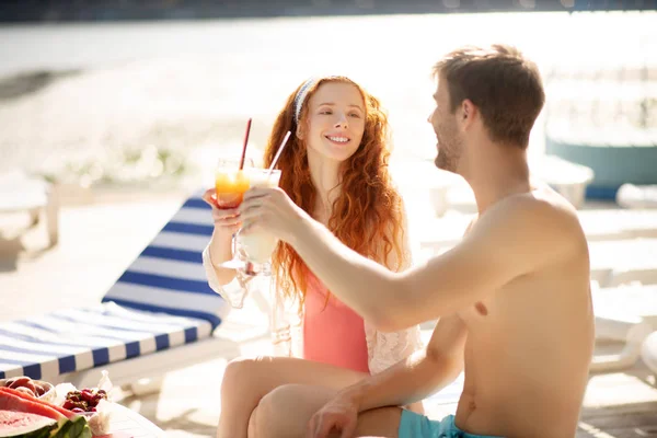 Red-haired girlfriend looking at man while chilling near pool — Stock Photo, Image
