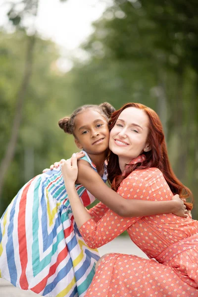 Aranyos vicces, sötét bőrű lány átölelve szép anyja — Stock Fotó