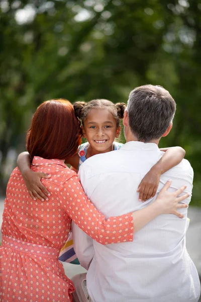 Dark-eyed African-American girl meeting her adoptive parents — Stock Photo, Image