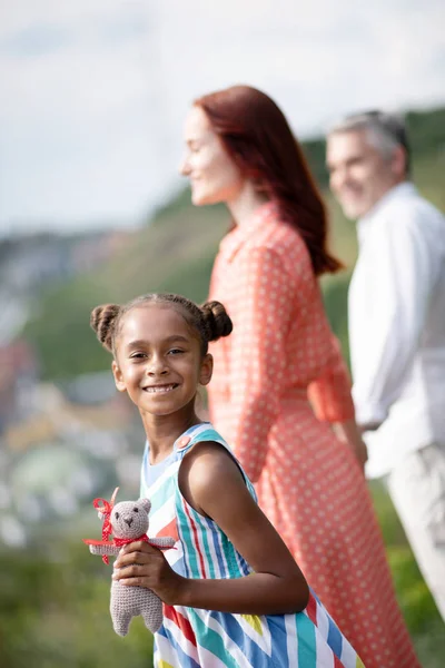 Menina de pele escura sorrindo enquanto passa o tempo com os pais — Fotografia de Stock