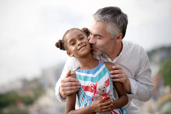 Grey-haired pai adotivo beijando sua linda filha de pele escura — Fotografia de Stock