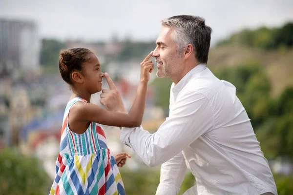 African-American daughter touching nose of her foster father