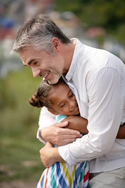 Любящий отец обнимает свою милую темнокожую дочь — стоковое фото