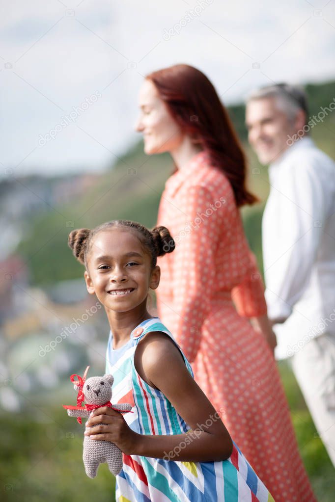 Dark-skinned girl smiling while spending time with parents