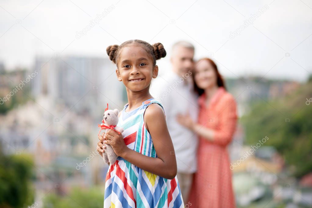Cute dark-skinned girl holding her favorite toy