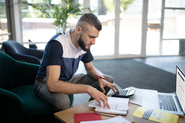 Бизнесмен работает над расчетами, сидя в офисе
