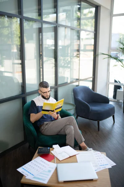 Empresario sentado en sillón y libro de lectura — Foto de Stock