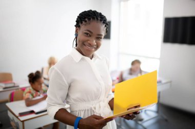 Beyaz bluz giyen neşeli öğretmen iş yerinde iyi hissediyor