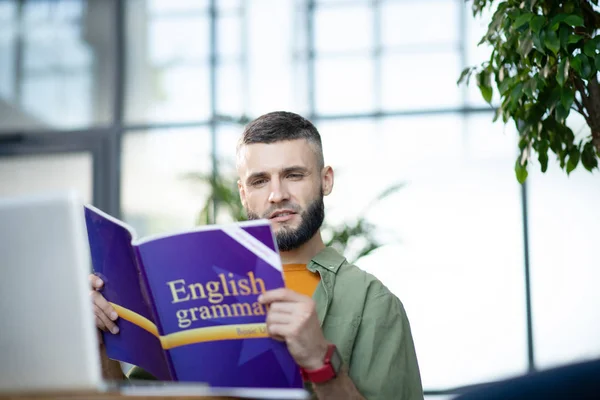 Bearded young businessman studying English grammar