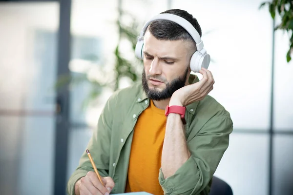 Bearded young man listening to recording and making test — Stock Photo, Image