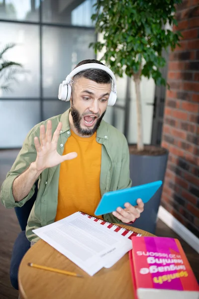 Student wearing earphones using tablet while studying — Stock Photo, Image