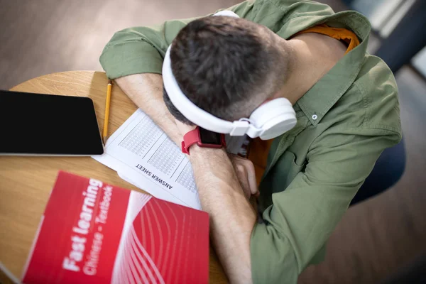 Estudante usando fones de ouvido e relógio inteligente sentindo sonolento — Fotografia de Stock