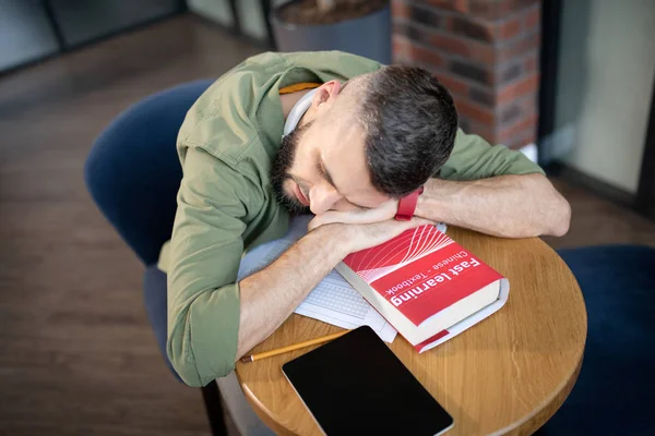 Estudante dormindo no livro deitado perto da mesa na mesa — Fotografia de Stock