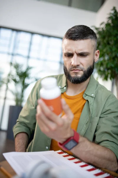 Hombre barbudo leyendo la descripción de las pastillas para dormir — Foto de Stock