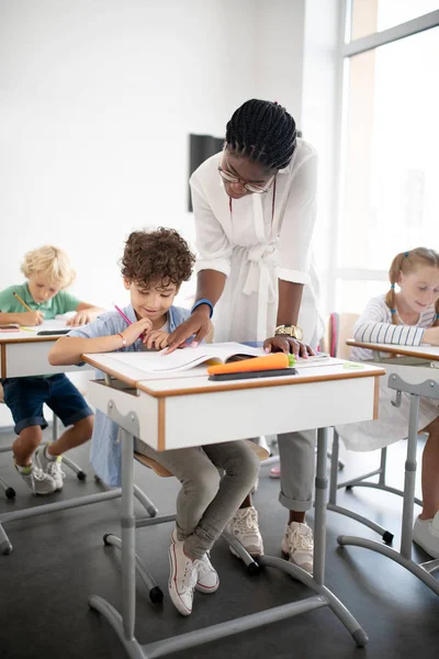 Afro-Amerikaanse leraar komt naar schattig krullend jongen — Stockfoto