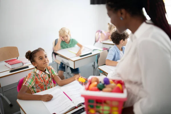 Niña tomando bola de color de profesor en la lección —  Fotos de Stock