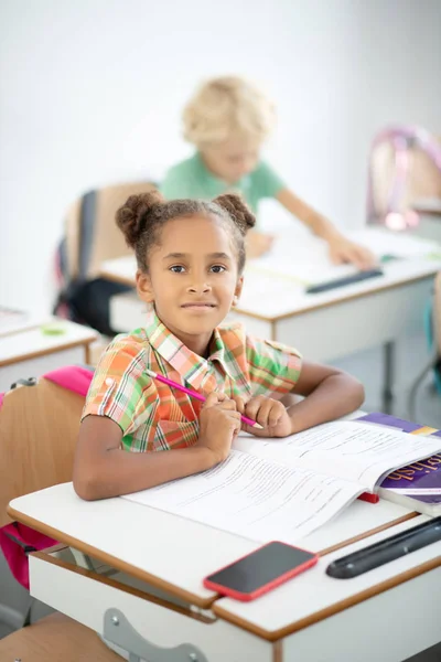 Σκούρα μάτια κορίτσι κρατώντας μολύβι ενώ κάθεται στο γραφείο — Φωτογραφία Αρχείου