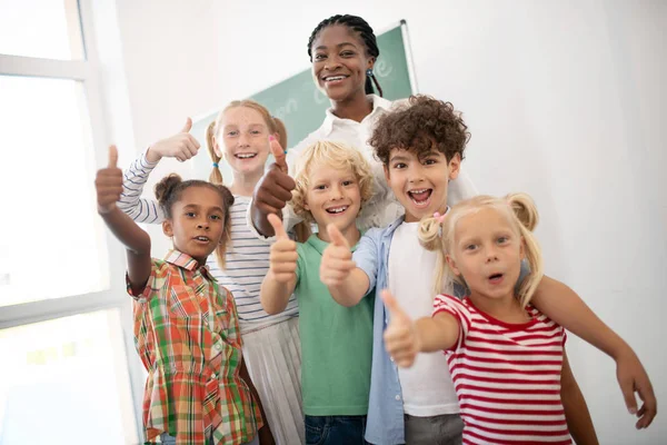 Dzieci pokazując kciuki w górę, podczas gdy uczucie niesamowite po lekcji — Zdjęcie stockowe