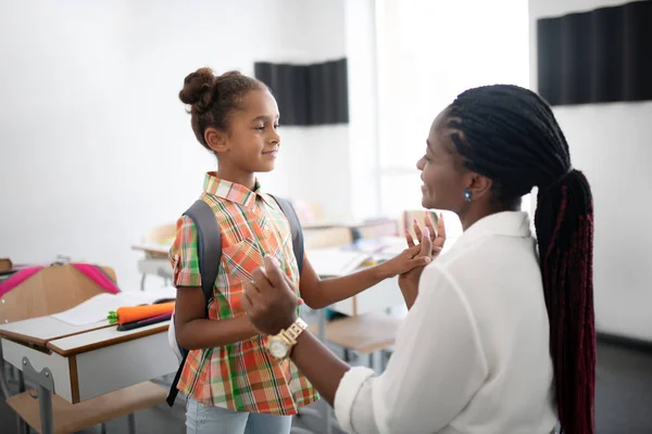 Dark-skinned teacher supporting little African-American girl