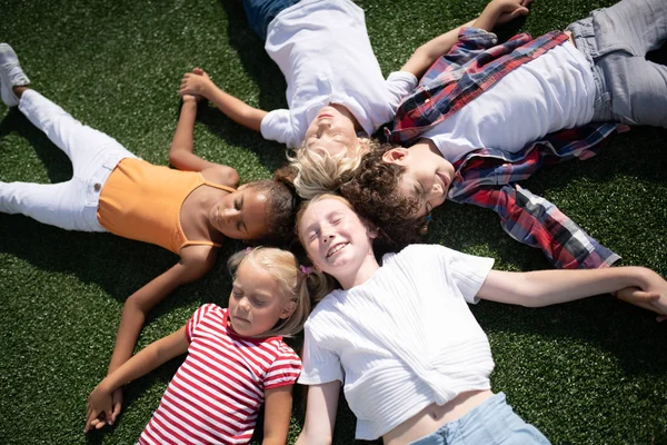 Παιδιά που ξαπλά στο γρασίδι και απολαμβάνοντας ηλιόλουστη μέρα — Φωτογραφία Αρχείου