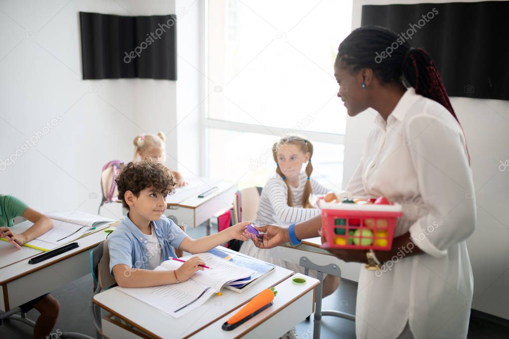 Curly dark-haired boy getting appraisal from teacher
