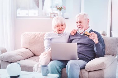 Sakallı yaşlı adam eşi ile online banka kartı alışveriş tutan