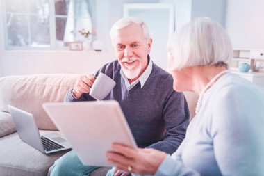 Sakallı koca, karısı onu tablette gösterirken fotoğrafları izliyor