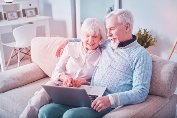 Modern beaming grandparents having video chat with their grandchildren