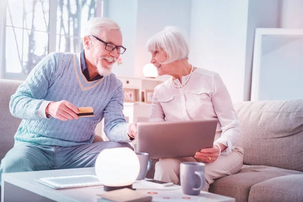 Modern elderly man and woman processing payment while paying online