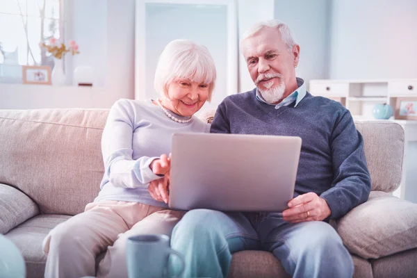 Modern gepensioneerd paar gevoel betrokken bij het kijken naar film op hun laptop — Stockfoto