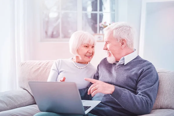 Film kijken. Modern gepensioneerd paar gevoel betrokken bij het kijken naar film op hun laptop terwijl zittend op de Bank — Stockfoto