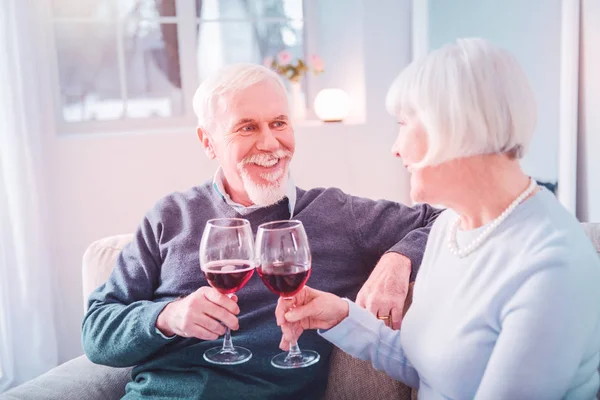 Couple of beaming pensioners clanging their glasses having romantic dinner — Stock Photo, Image