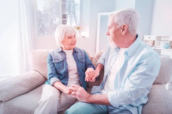 Loving beaming wife holding hands of her bearded grey-haired husband — Stock Photo, Image