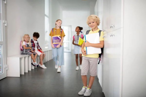 Pojke klädd i shorts och t-shirt stående i skolan korridor — Stockfoto