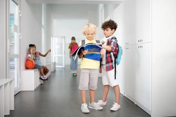 Niños con pantalones cortos y zapatillas de deporte de pie y leyendo juntos — Foto de Stock