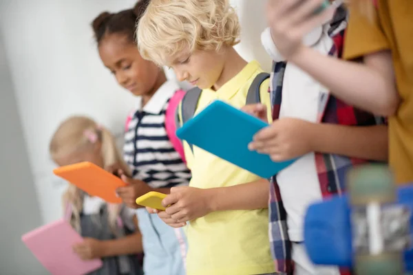 Barn beroende av prylar som spelar spel i skolan korridor — Stockfoto