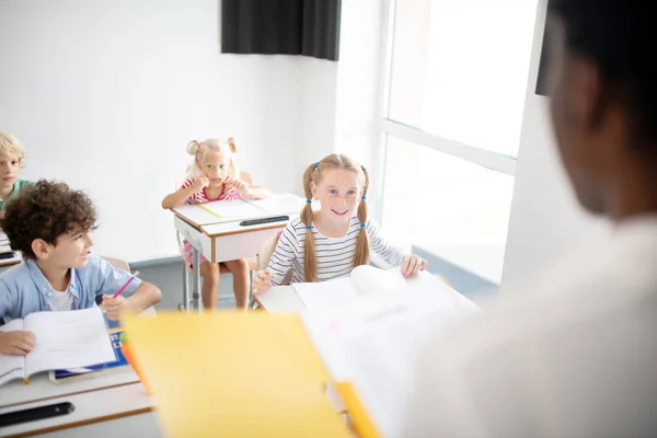 Lächelnde Kinder hören ihrem Lehrer aufmerksam zu — Stockfoto