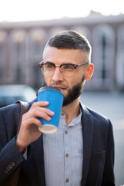 Ofise yürürken kahve içen işadamı