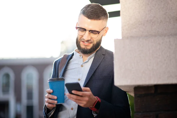 ビジネスマンは、電話でメッセージを読んで外で休憩を楽しんでいます — ストック写真