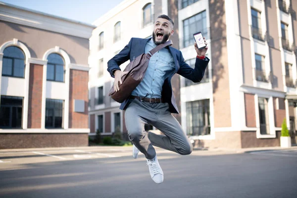 Hombre guapo saltando después de leer el mensaje de la compañía — Foto de Stock