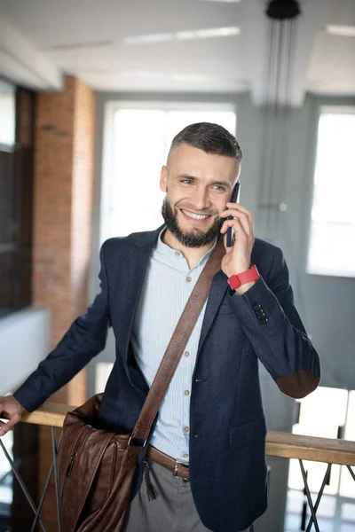 Smiling businessman speaking with colleague by the phone