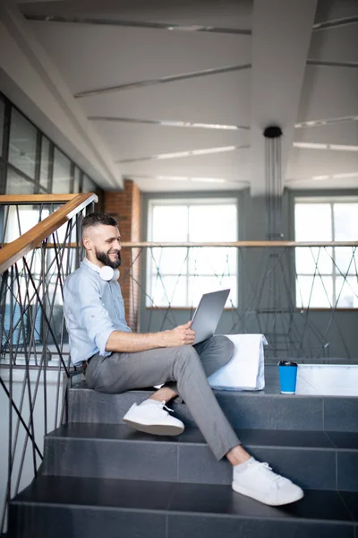 Bearded man holding his silver laptop and working hard — Stock Photo, Image