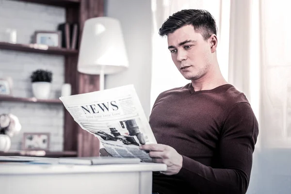 Geïnteresseerde man lezing verse krant thuis — Stockfoto
