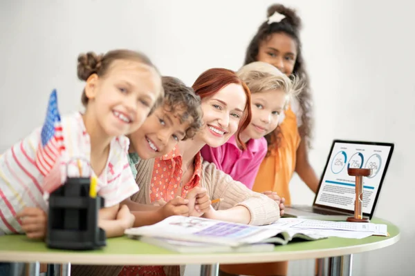 Lehrer und Kinder sitzen am Tisch neben Laptop — Stockfoto