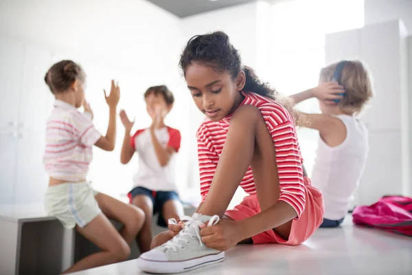 Chica de piel oscura atando sus zapatillas preparándose para la clase de PE — Foto de Stock